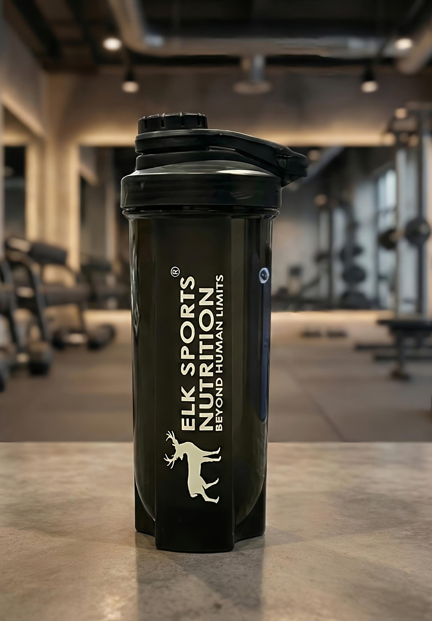 Black shaker bottle with Elk Sports Nutrition logo in a gym setting